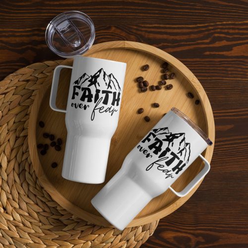 Overhead view of a round wooden tray holding two Faith Over Fear Travel Mugs on a woven placemat. The mugs display the text "Faith over fear" with an illustration of mountains. Coffee beans are scattered around the tray, and one mug has its lid off and placed beside it—ideal religious gifts for any occasion. christian gifts, religious gifts, gifts of faith, faith based gifts, faith inspired gifts