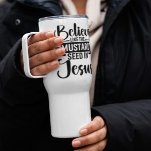 A person wearing a dark coat holds a Believe Like The Mustard Seed In Jesus Travel Mug with a handle in both hands. The travel mug has the text "Believe like the mustard seed in Jesus" printed in bold black letters. christian gifts, religious gifts, gifts of faith, faith based gifts, faith inspired gifts