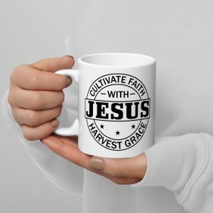 A person wearing a white sweater holds a Cultivate Faith With Jesus Harvest Grace Coffee Cup from Judeo Gifts in both hands. The white mug features black text that reads "Cultivate Faith with Jesus" and "Harvest Grace," accompanied by small star graphics on the design. christian gifts, religious gifts, gifts of faith, faith based gifts, faith inspired gifts