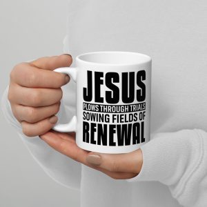 A person wearing a white long-sleeve shirt holds the "Jesus Plows Through Trials Sowing Fields Of Renewal Coffee Cup," with black text reading, "Jesus plows through trials sowing fields of renewal." The person's nails, painted light brown, add a touch of warmth to this heartfelt Christian gift. christian gifts, religious gifts, gifts of faith, faith based gifts, faith inspired gifts