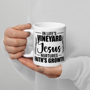 A person wearing a white sweater holds the "In Life's Vineyard Jesus Nurtures Faith's Growth Coffee Cup," making it a perfect religious gift. christian gifts, religious gifts, gifts of faith, faith based gifts, faith inspired gifts