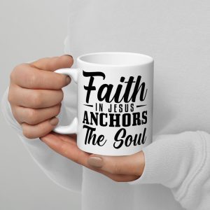 A person holding a "Faith In Jesus Anchors The Soul Coffee Cup" with a motivational message printed on it. The cup, an ideal Christian gift, reads "Faith in Jesus anchors the soul" in bold black lettering. The person is wearing a light-colored long-sleeve shirt. christian gifts, religious gifts, gifts of faith, faith based gifts, faith inspired gifts