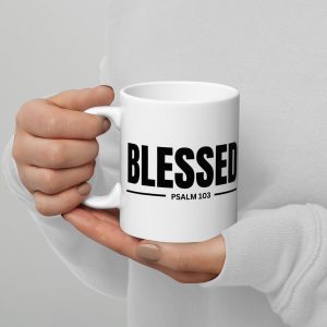 A person holding a Blessed "Psalm: 103" Coffee Cup in both hands. The mug features the word "BLESSED" in bold black letters, with "PSALM 103" written underneath it. The person, wearing a white long-sleeve shirt from Jesus T Shirts, stands against a plain light gray background. christian gifts, religious gifts, gifts of faith, faith based gifts, faith inspired gifts