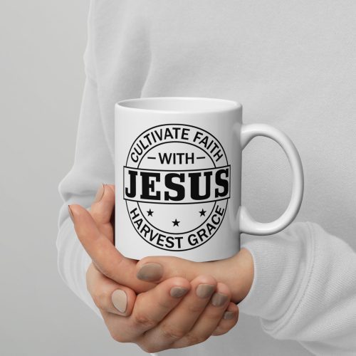 A person in a white sweater holds the "Cultivate Faith With Jesus Harvest Grace Coffee Cup," which features black text saying "Cultivate Faith with Jesus, Harvest Grace" inside a circular emblem adorned with stars. This Christian gift mug is held tenderly with both hands, showcasing neatly manicured nails. christian gifts, religious gifts, gifts of faith, faith based gifts, faith inspired gifts