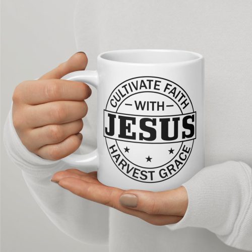 A person wearing a white long-sleeve shirt holds the "Cultivate Faith With Jesus Harvest Grace Coffee Cup" from Judeo Gifts, featuring black text that reads "Cultivate Faith with Jesus" and "Harvest Grace." The phrases are encircled by circular borders and accented with small stars, making it one of the cherished gifts of faith. christian gifts, religious gifts, gifts of faith, faith based gifts, faith inspired gifts