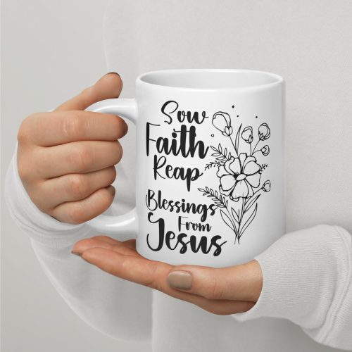 A person wearing a light grey long-sleeve shirt holds the "Sow Faith Reap Blessing From Jesus Coffee Cup" adorned with black floral illustrations and elegant script, making it a perfect religious gift. christian gifts, religious gifts, gifts of faith, faith based gifts, faith inspired gifts